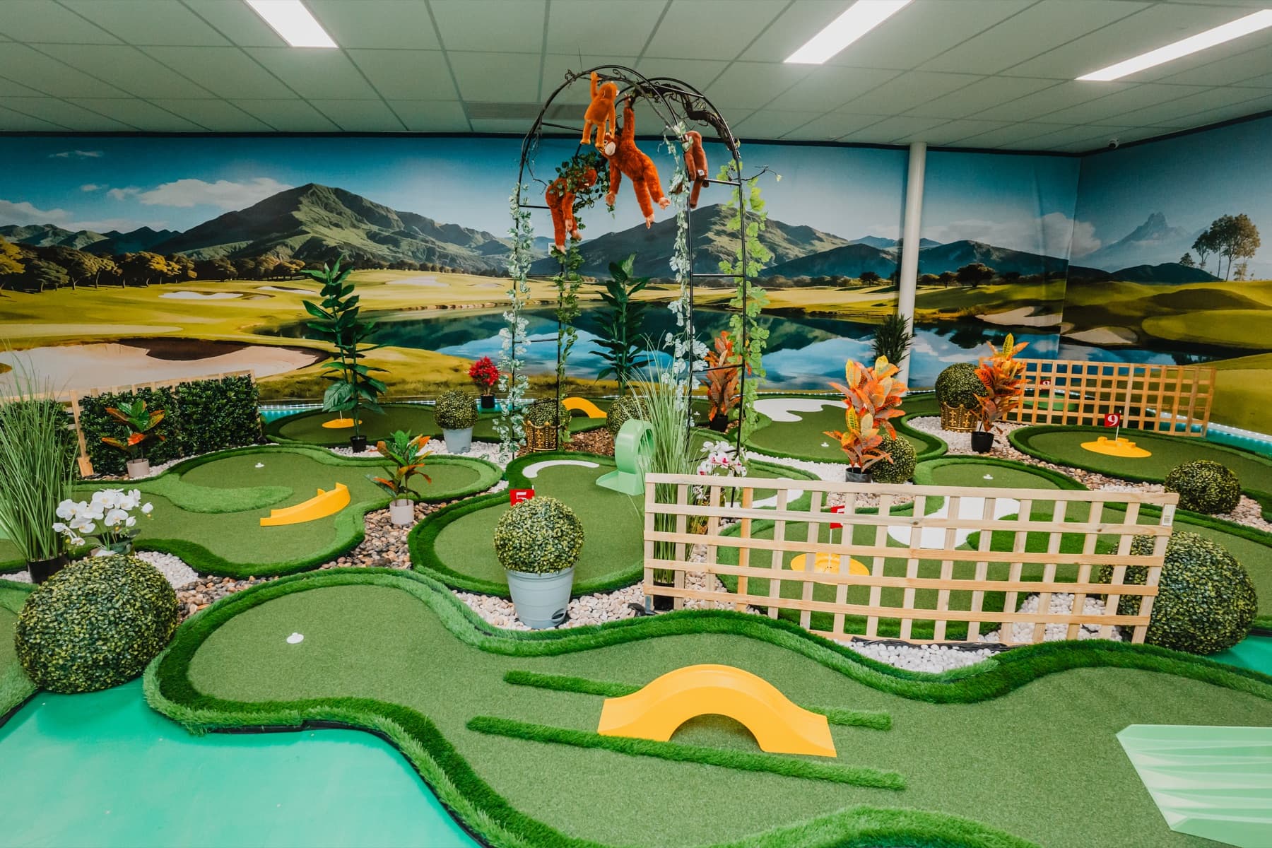 Photograph of the indoor course's vine arch, orange monkeys and winding putting lanes